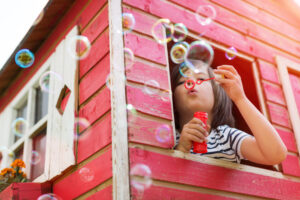 young girl blowing bubbles outside of treehouse