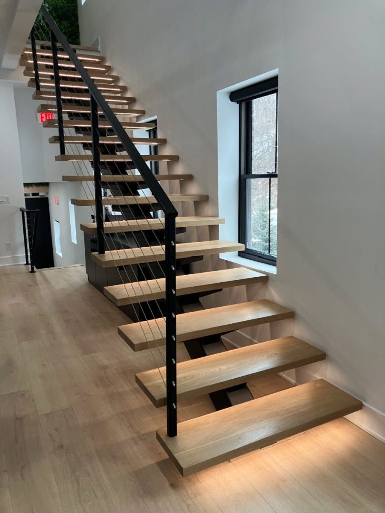 6x8" steel tube single stringer with carriers under the treads.
Treads are 8/4" red oak (1.75" thick after mill) with LED system. Steel railing with our custom cable railing system. All steel powder coated satin black.